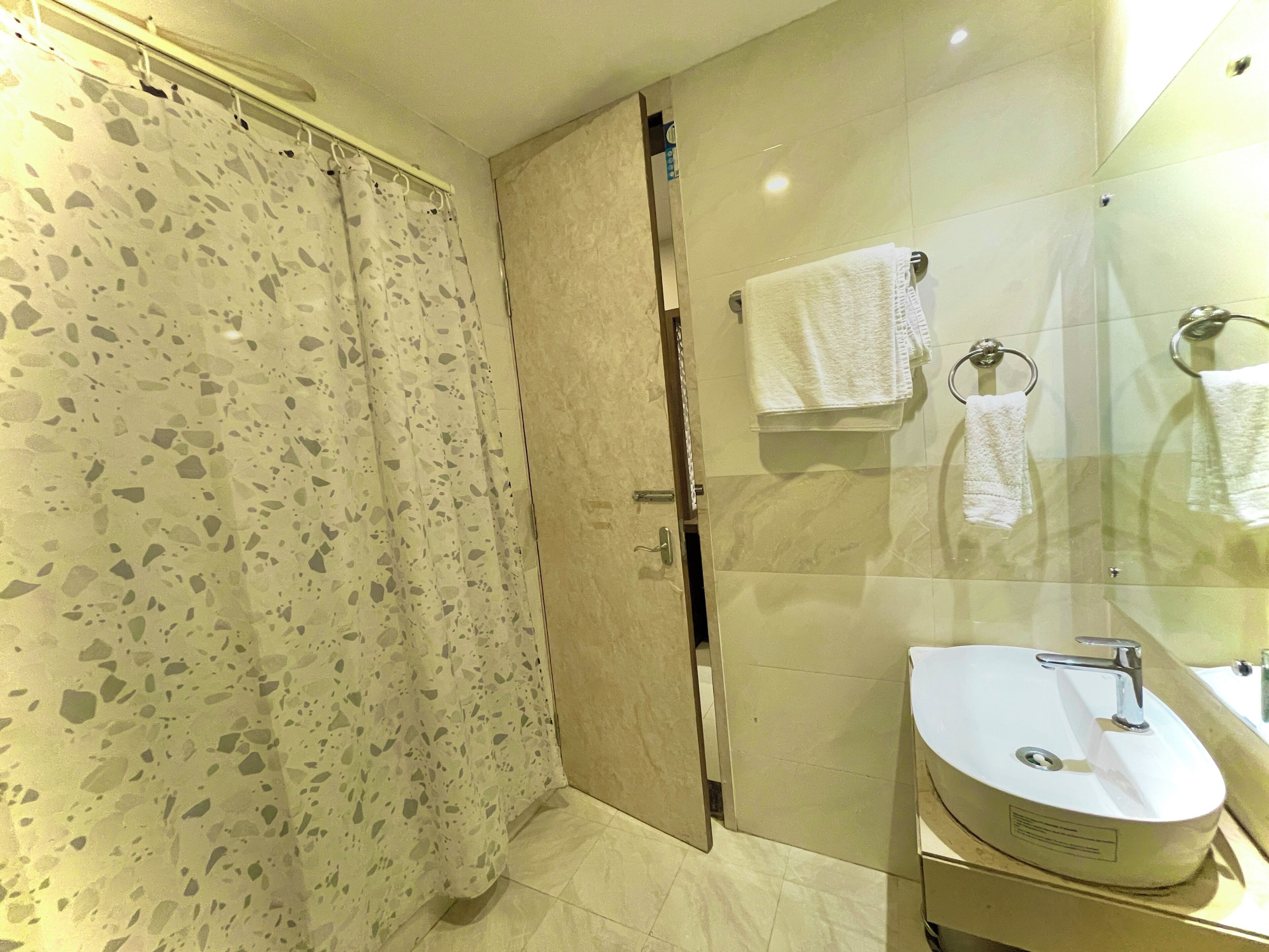A bathroom with a shower, a sink, and a glass-enclosed mirror.