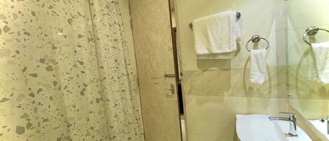 A bathroom with a shower, a sink, and a glass-enclosed mirror.