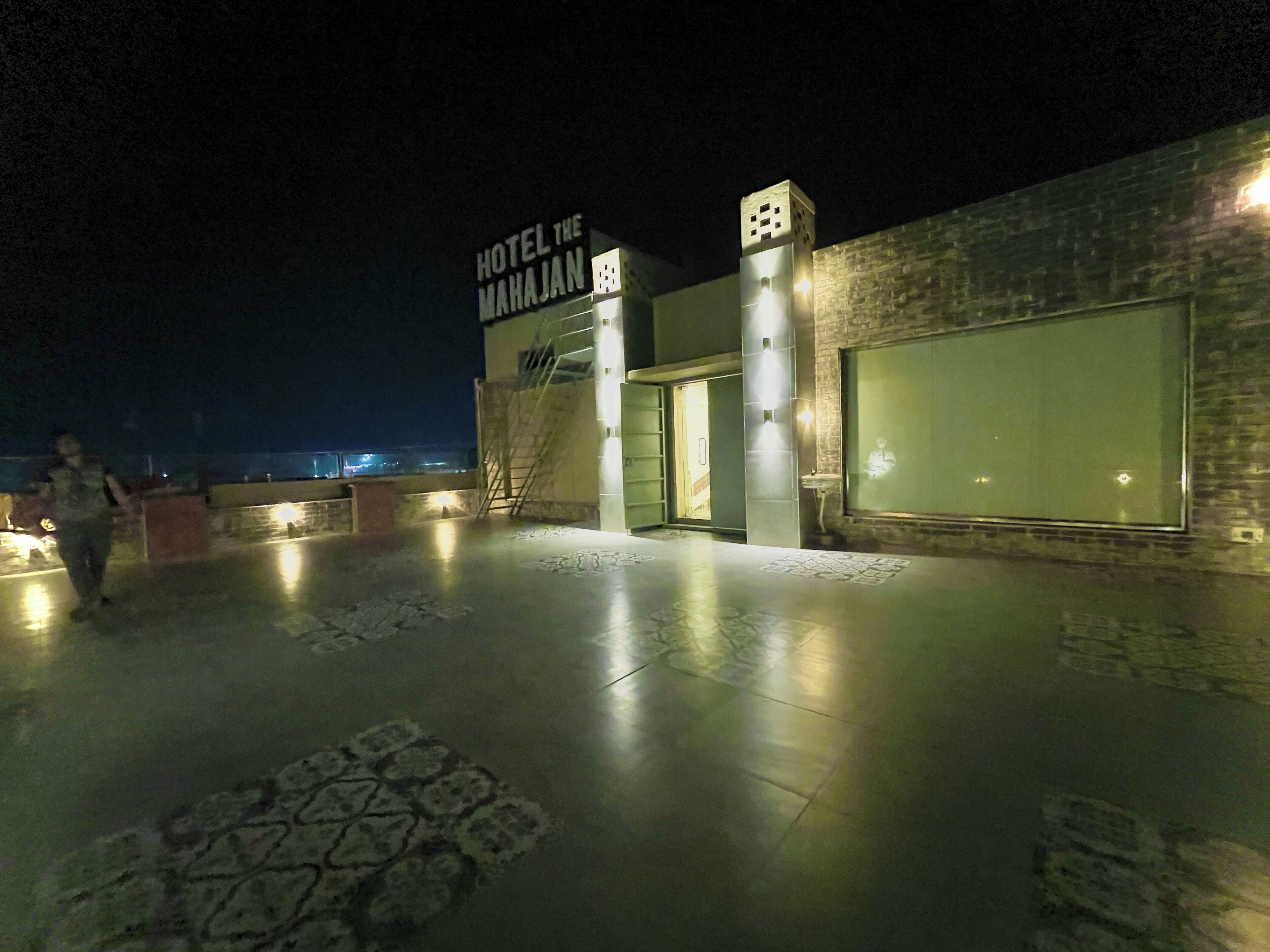 A hotel entrance with a sign reading "Hotel The Mahajan" at night.