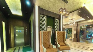 Un vestíbulo con dos sillones marrones con textura, un mostrador de recepción y una lámpara moderna.