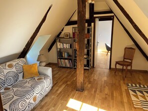 Cozy attic room with a comfortable sofa, bookshelf, and classic chair.