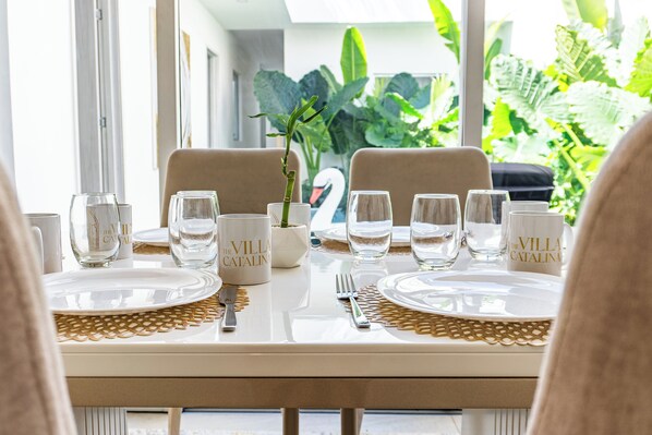 Une table à manger dressée avec des assiettes, des verres et des couverts, agrémentée d’un vase en forme de cygne et d’une plante placés au centre.