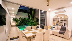 Un salon moderne avec un coin repas, un ensemble de canapés et une vue sur la piscine.