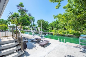 Un balcón con escalones que dan a una zona de piscina, rodeado de exuberante vegetación y vistas despejadas al agua.