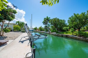 Un canal con un embarcadero, una silla de descanso y un edificio de techo blanco.