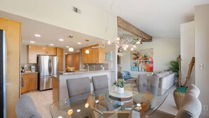 A modern kitchen with stainless steel appliances, a glass dining table, and contemporary furniture. - Palm Valley CC Charm | Outdoor Dining on the Patio, Desert Fun, Fitness, Spa, Tennis & Pickle Ball (Palm Desert)