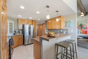 Une cuisine moderne avec des meubles en bois, des appareils en acier inoxydable et un îlot central doté de tabourets.