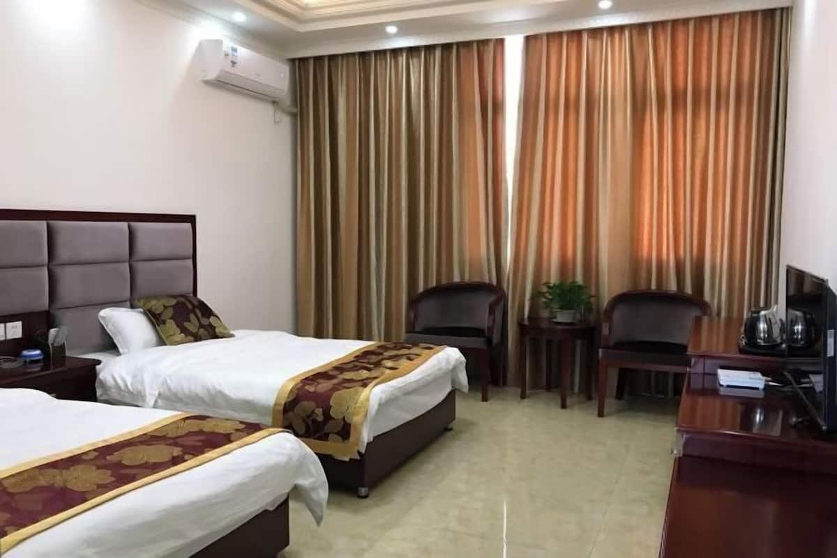 Une chambre d’hôtel avec deux lits, un bureau, une chaise et une petite table.