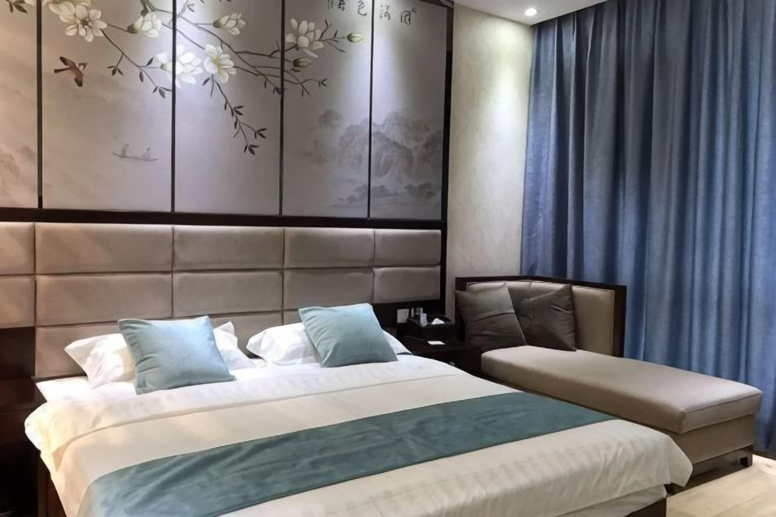Un dormitorio con cama, una banca, una mesita de noche y una pared con diseño floral.