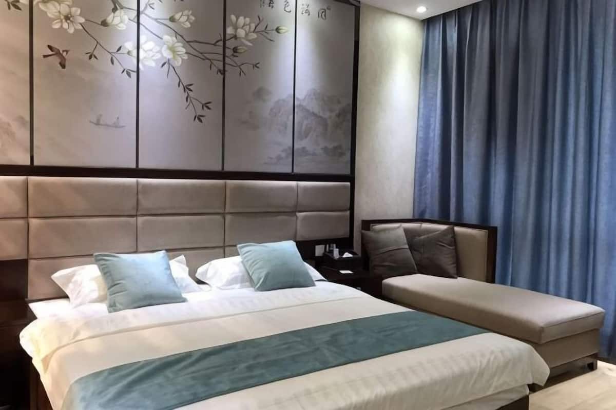 Une chambre à coucher comprenant un lit, un banc, une table de chevet et un mur orné d’un motif floral.