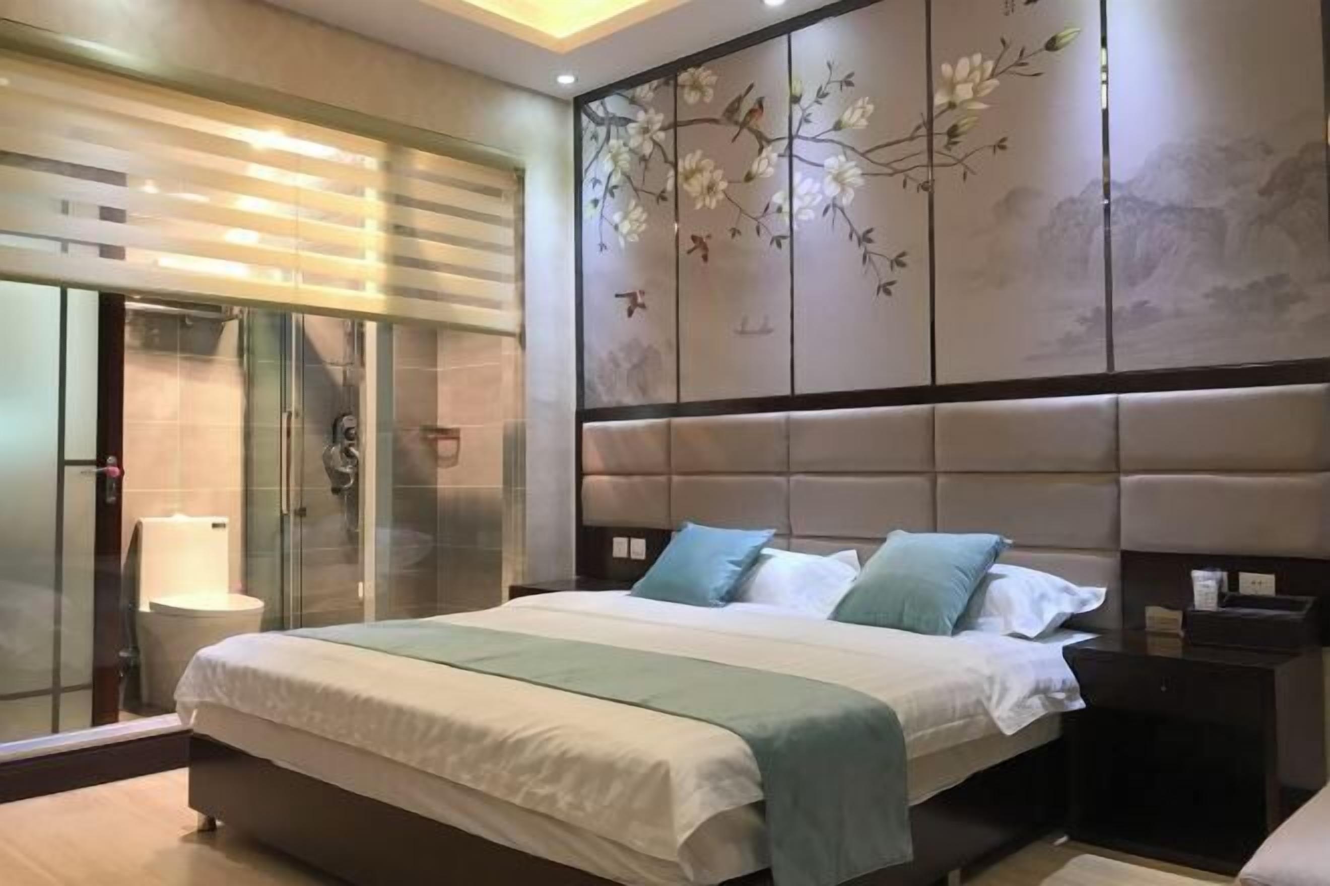 A modern bedroom with a large bed, a glass shower enclosure, and a decorative wall panel.