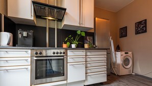 A compact kitchen with a built-in oven, a coffee machine, and a washing machine. - MUE Cubes (Basel)