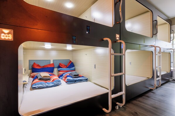 A train compartment with bunk beds, a ladder, and a small table. - MUE Cubes (Basel)