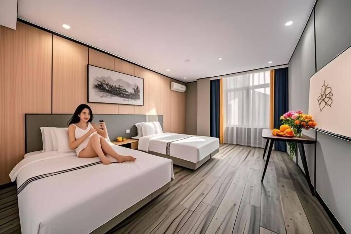 Una habitación de hotel moderna con dos camas, una mesita con flores y un cuadro en la pared.