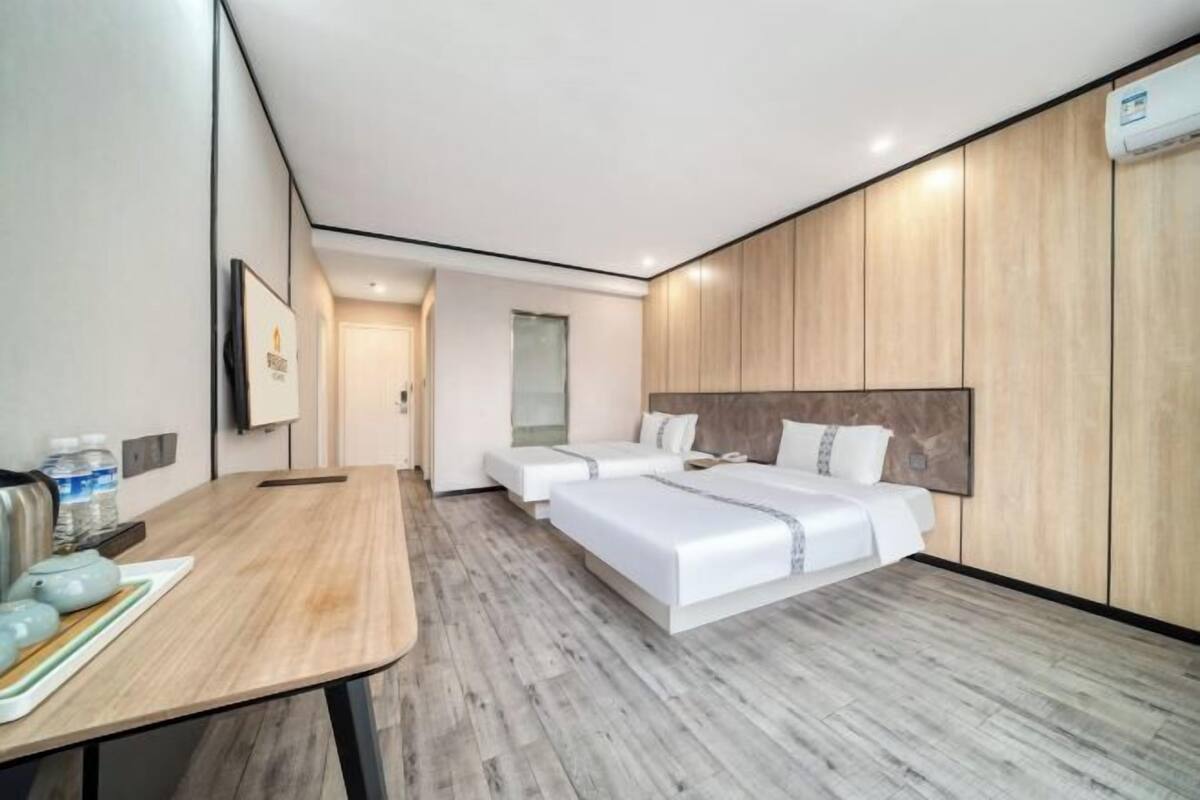 Una habitación de hotel moderna con dos camas, piso de madera y un escritorio con una silla.