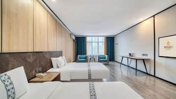 A modern hotel room with two beds, a small table, and a seating area with chairs.