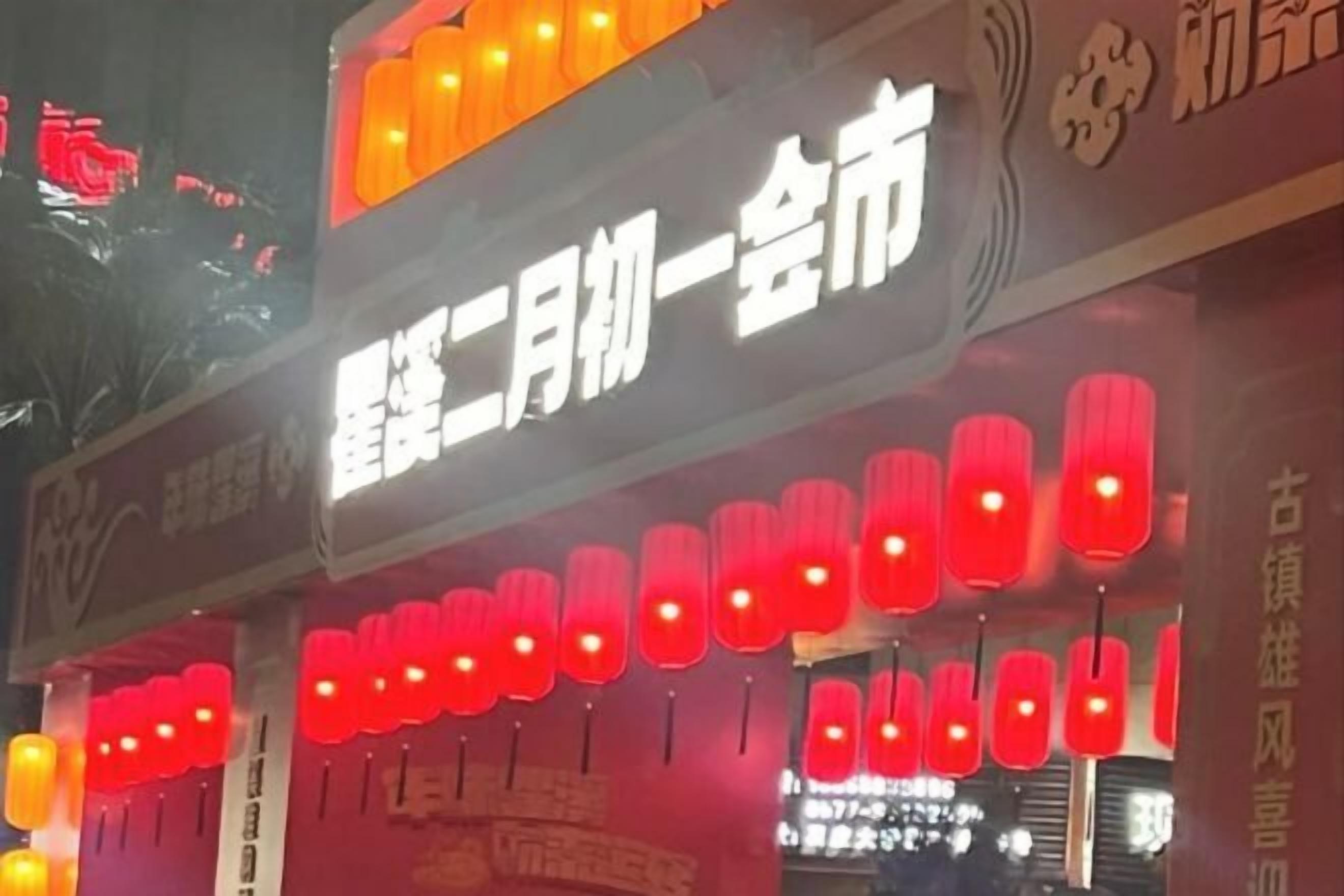 A building facade with illuminated signs and traditional red lanterns.