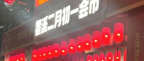 A building facade with illuminated signs and traditional red lanterns.