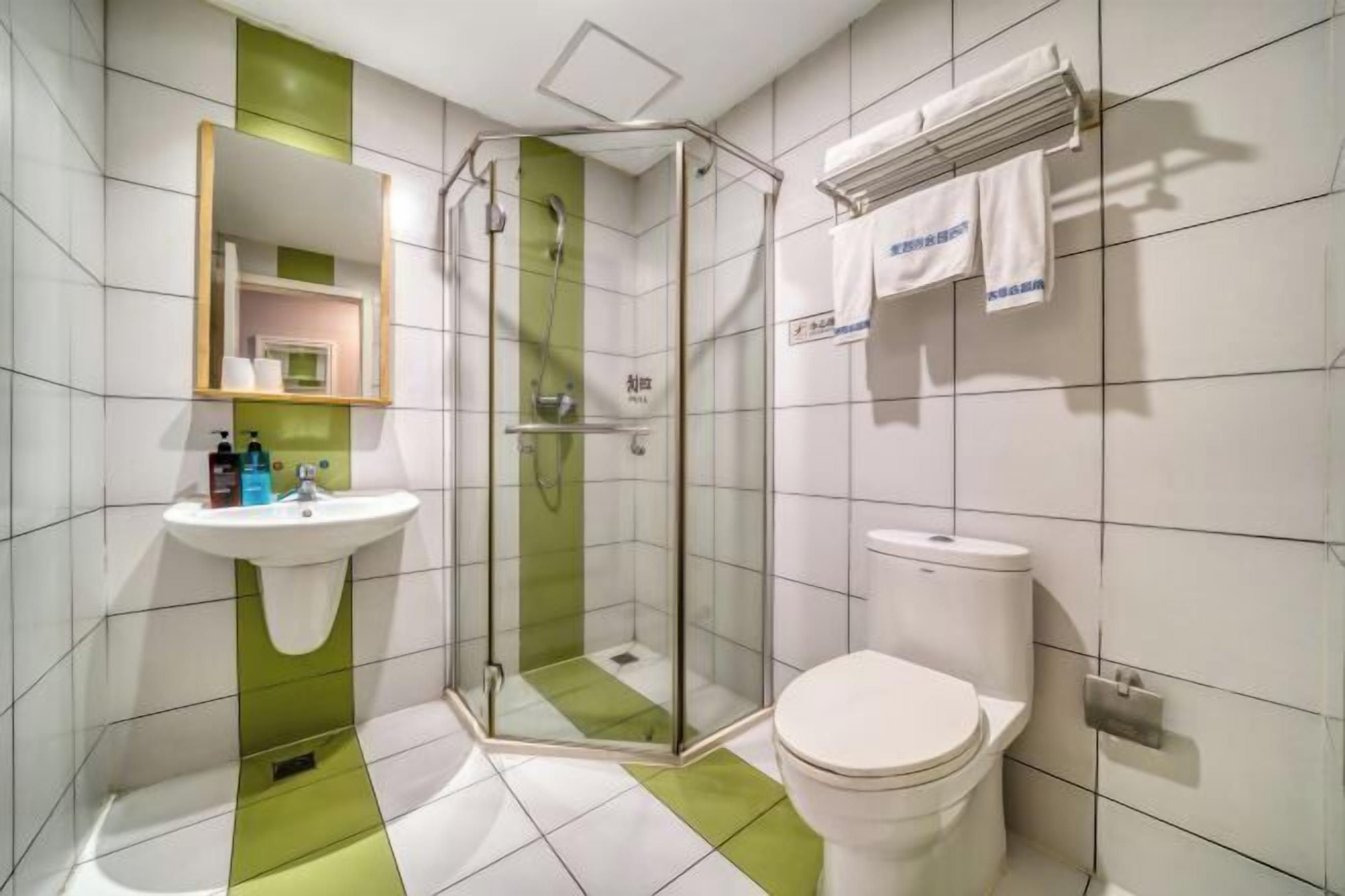 A modern bathroom with a glass-enclosed shower, a white toilet, and a sink with a mirror above it.