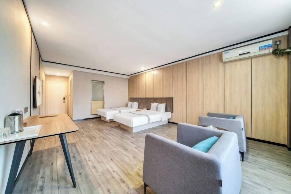Una habitación de hotel moderna con piso de madera, una cama, un escritorio y dos sillas.