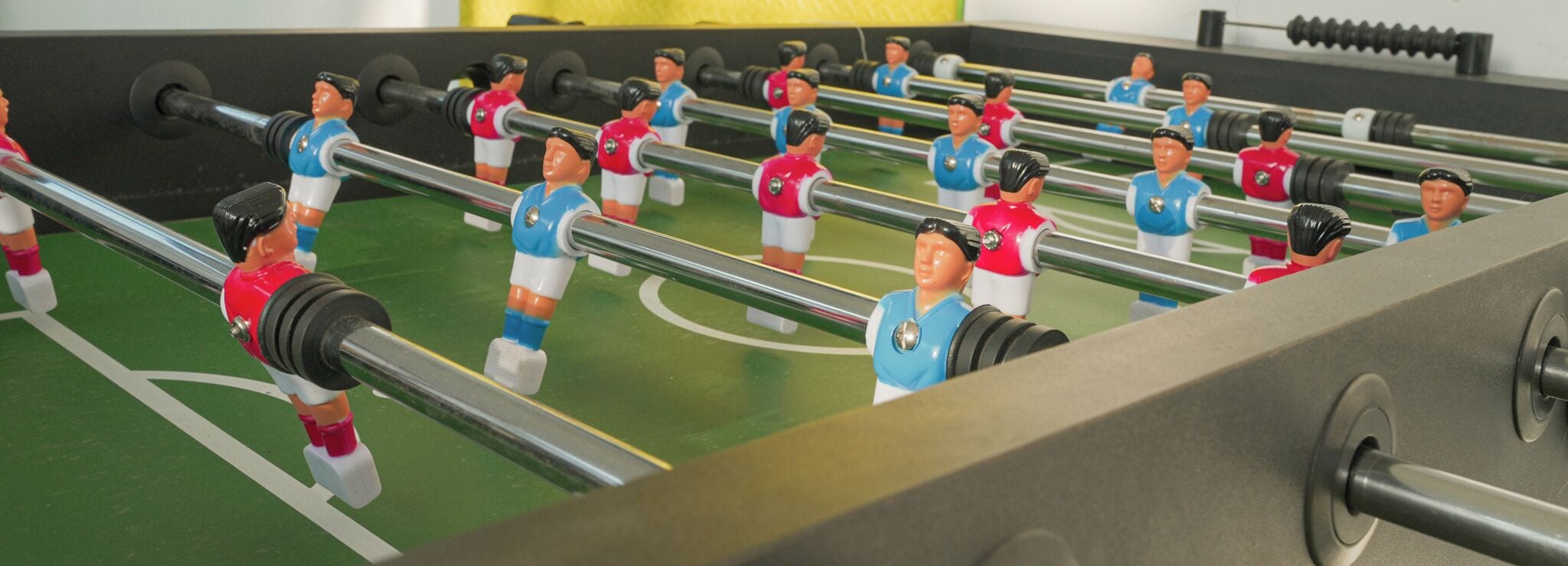 Una mesa de fútbolín con varios jugadores uniformados en rojo y azul.