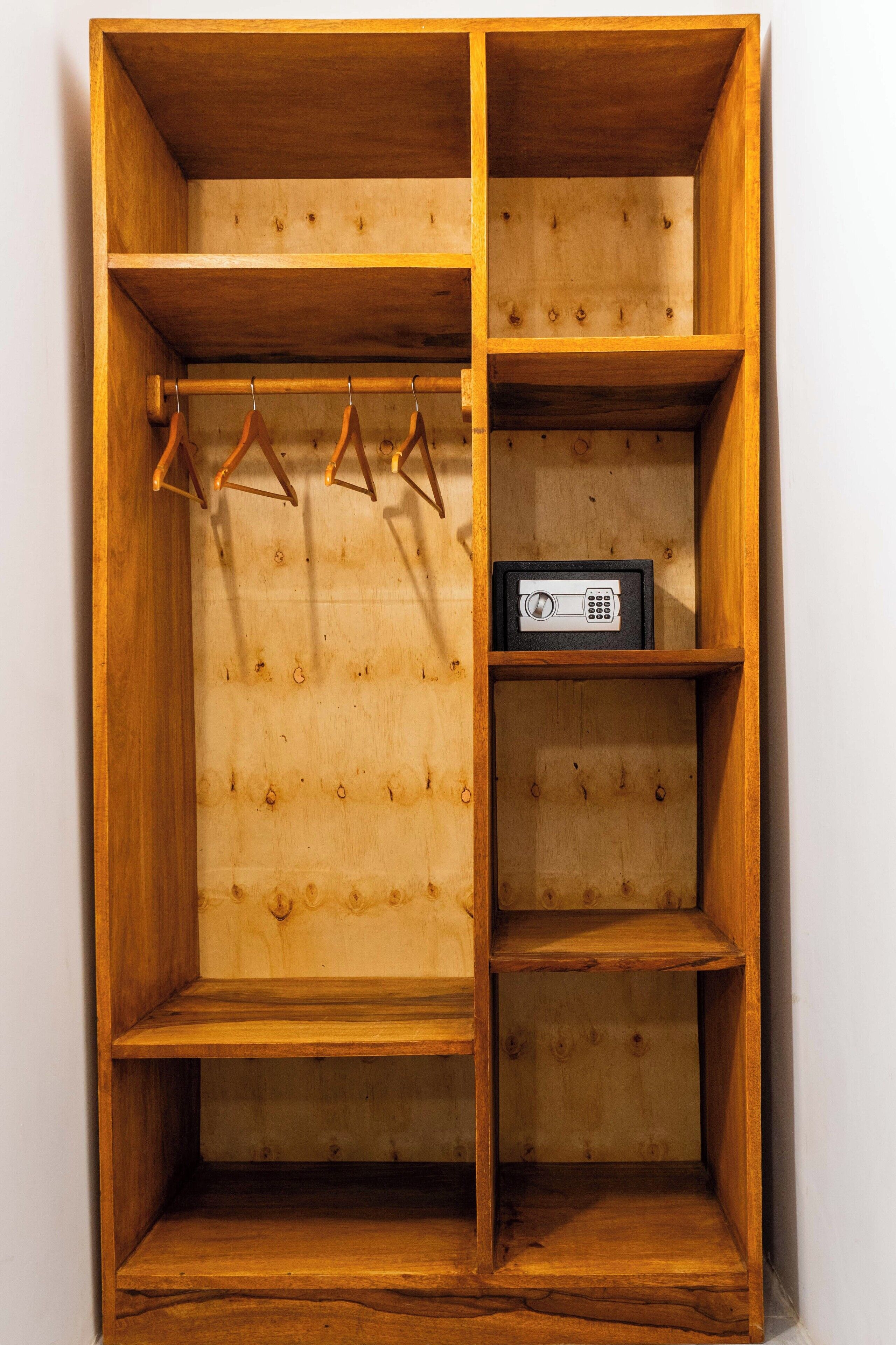 Un armario de madera con varios estantes y una barra para colgar.