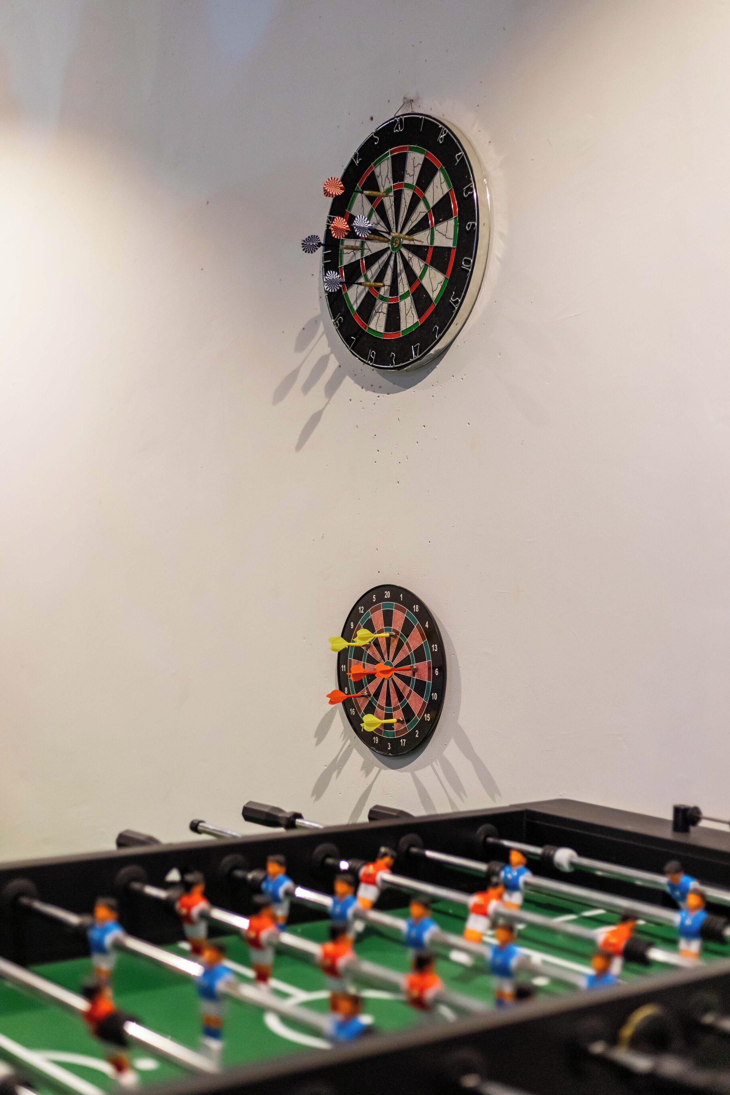 To dartskiver på en væg, med et fodboldbord i forgrunden.