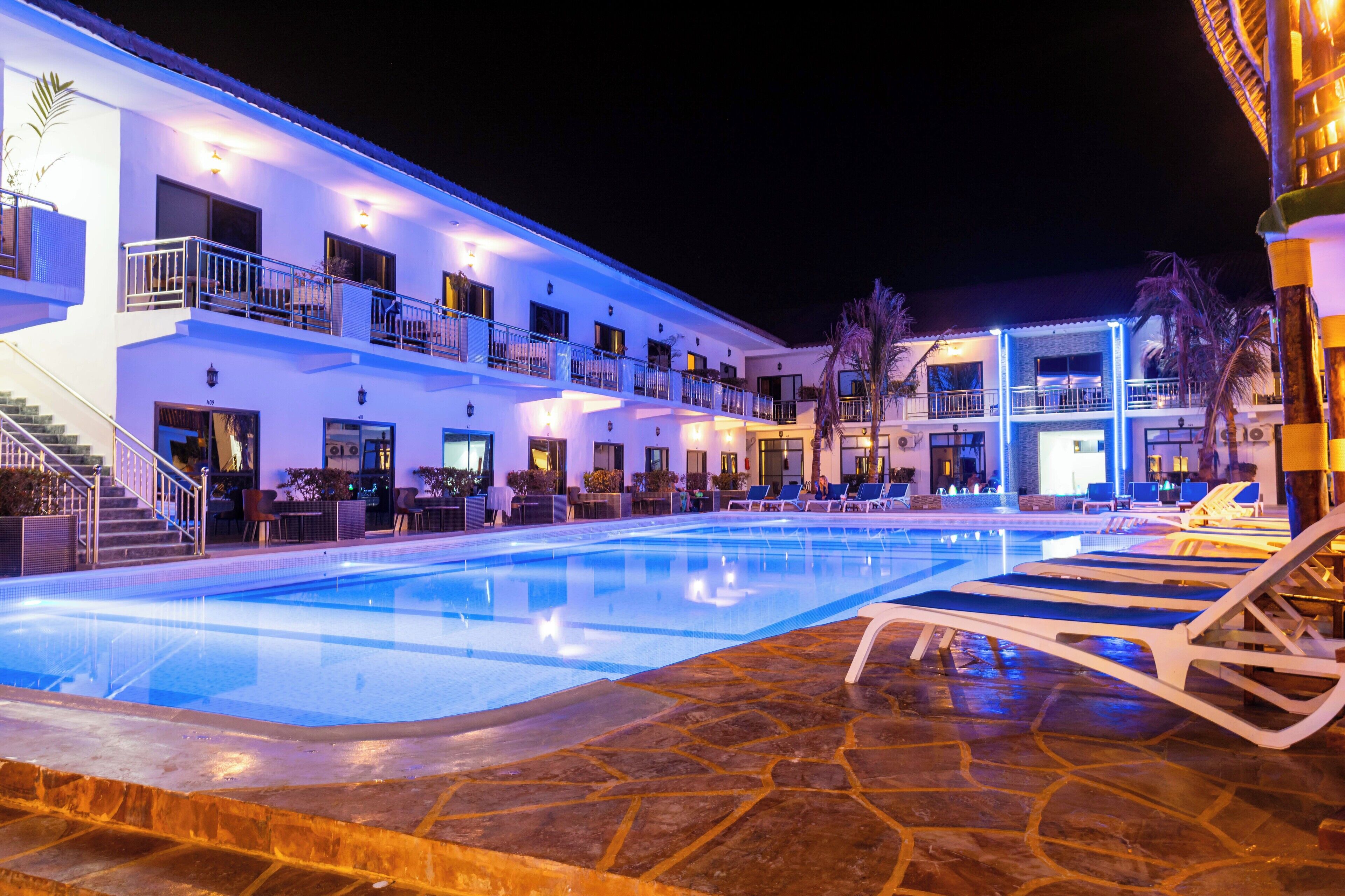 Un hotel con piscina, varios balcones y zonas de estar al aire libre.