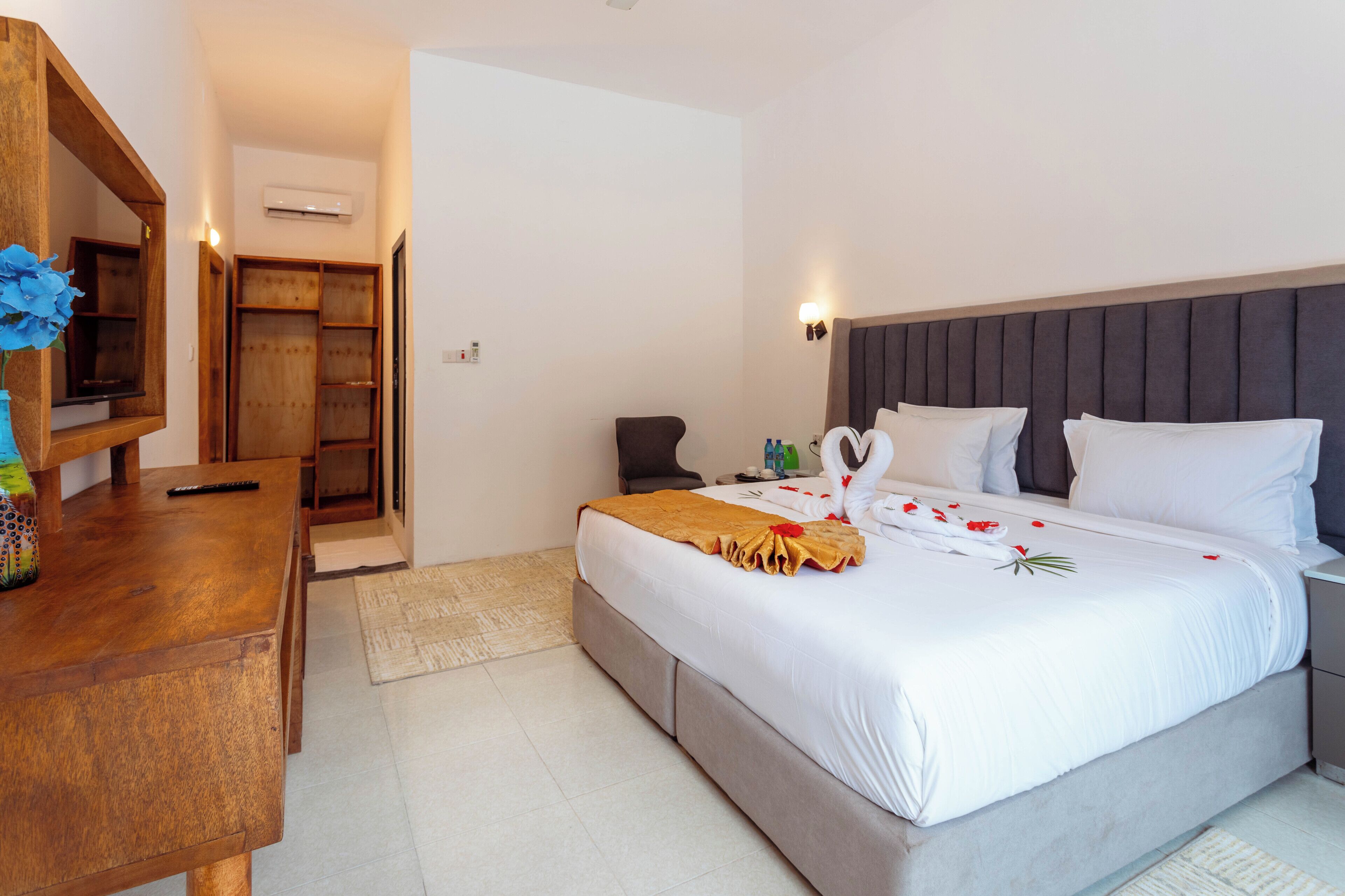 A hotel room with a bed, bedside table, and a wooden desk.