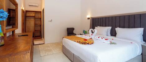 A hotel room with a bed, bedside table, and a wooden desk.