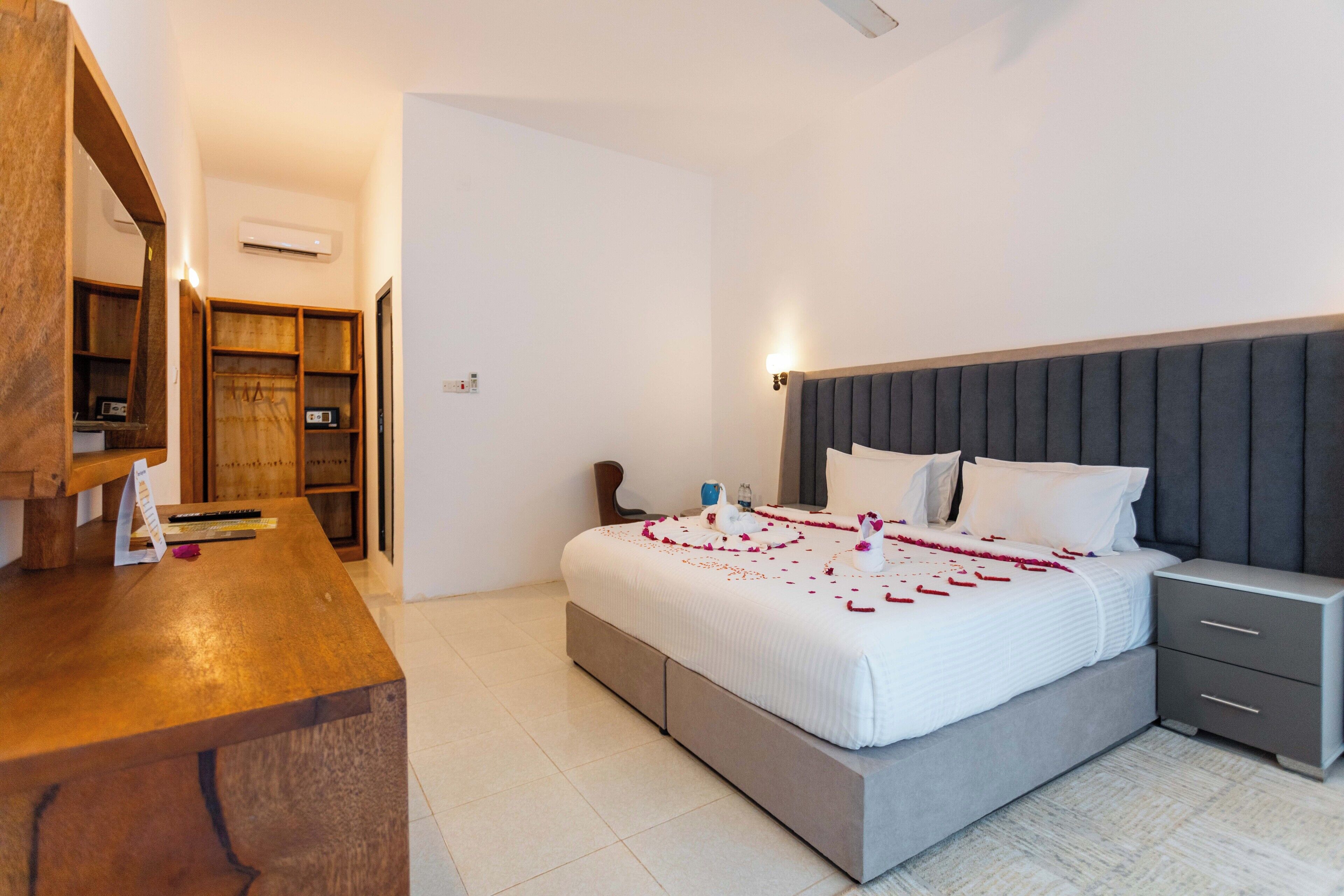 A bedroom with a large bed, bedside tables, a wooden desk, and a wardrobe.