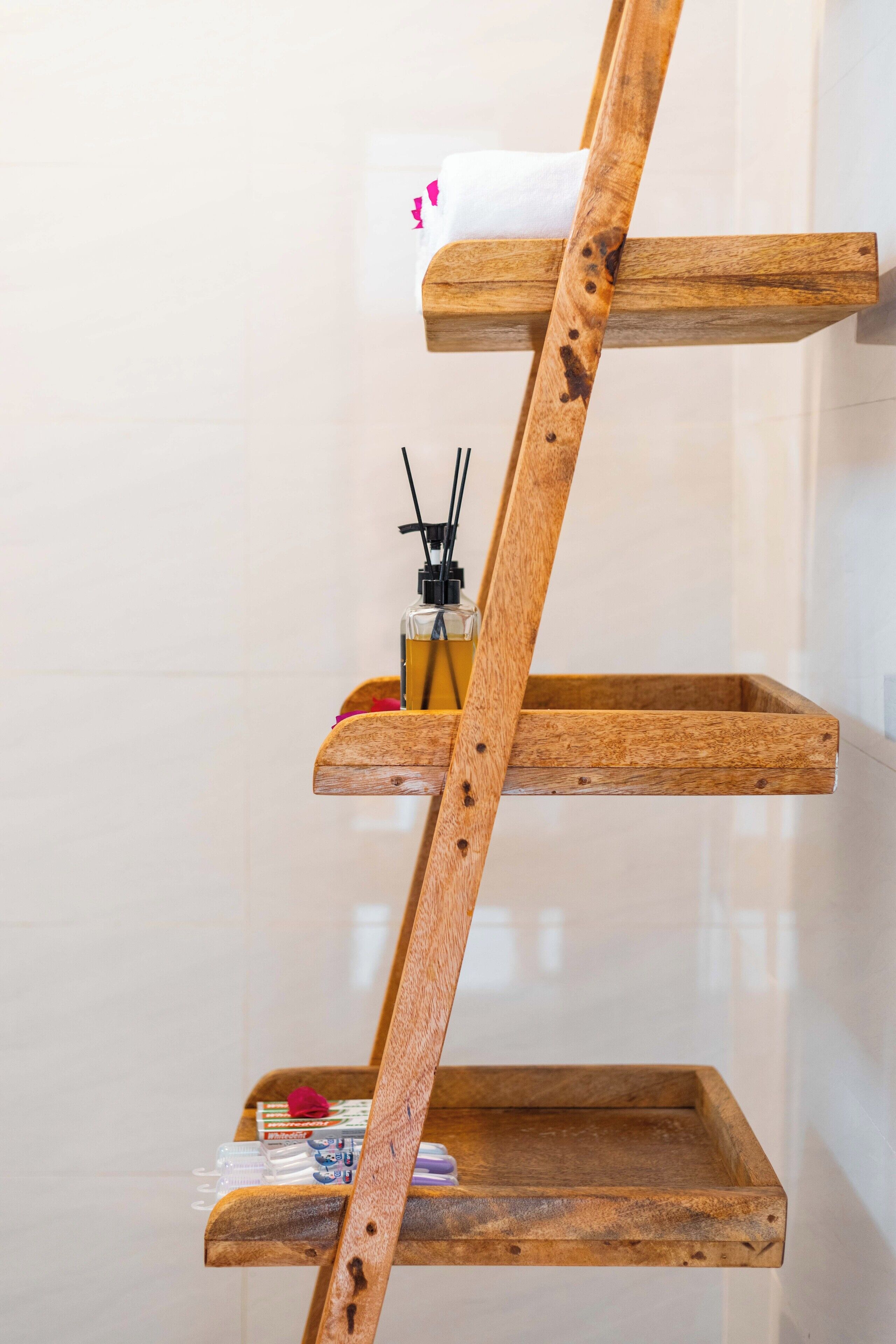 A wooden shelf unit with a bottle of hand sanitizer and a small item on the top shelf.