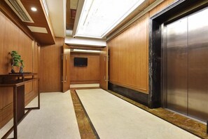 A hotel lobby with a reception desk, a flat-screen TV, and an elevator. - Chongqing Yuhao Hotel (Chongqing)