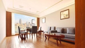 A modern living room with a wooden floor, a grey sofa, a coffee table, and a dining area with chairs and a table. - Chongqing Yuhao Hotel (Chongqing)