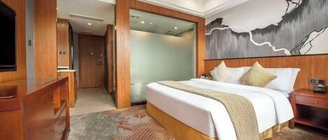 A hotel room with a large bed, a wooden dresser, a television, and a painting on the wall.