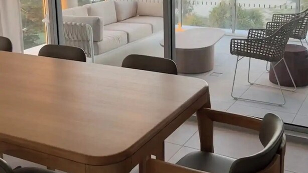 A modern dining area with a large table and chairs, a sofa, and a balcony with a view of the ocean. - Apartment in Palm Beach (Palm Beach)
