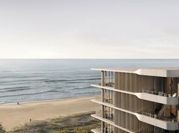 Ein modernes, mehrstöckiges Gebäude mit Balkonen mit Blick auf einen Strand und den Ozean.