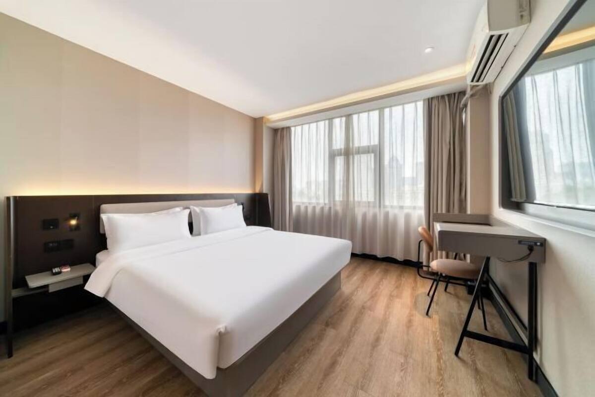 A modern hotel room with a large bed, a desk, and a chair.