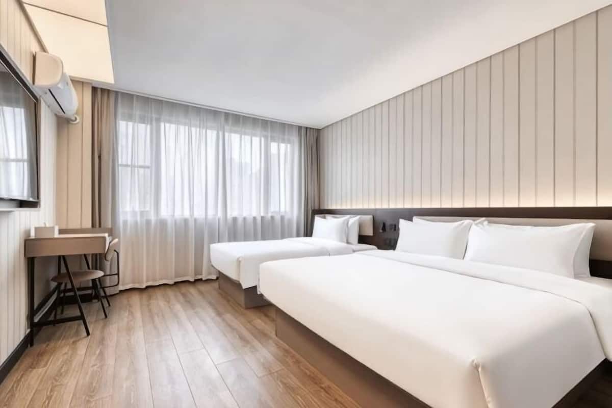 A hotel room with a large bed, a desk, and a chair.