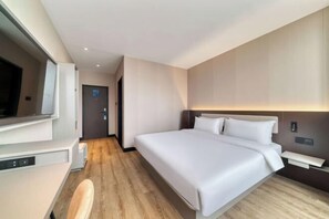 Une chambre d’hôtel avec un lit, un bureau et un téléviseur.