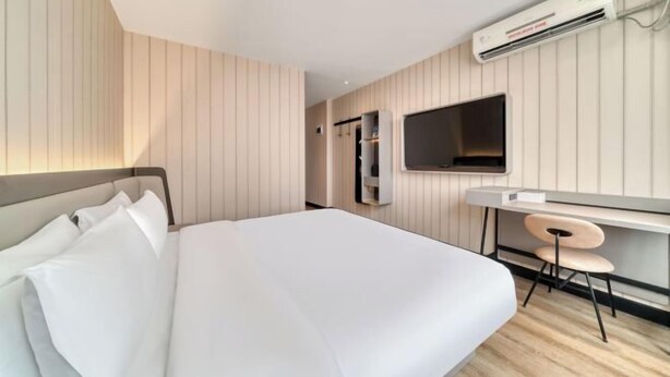 A hotel room with a bed, a desk with a chair, a TV, and an air conditioning unit. - Hanting Hotel (Hangzhou)