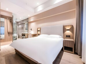 A modern bedroom with a large bed, bedside tables, a desk, and a mirror. - Hanting Hotel (Hangzhou)