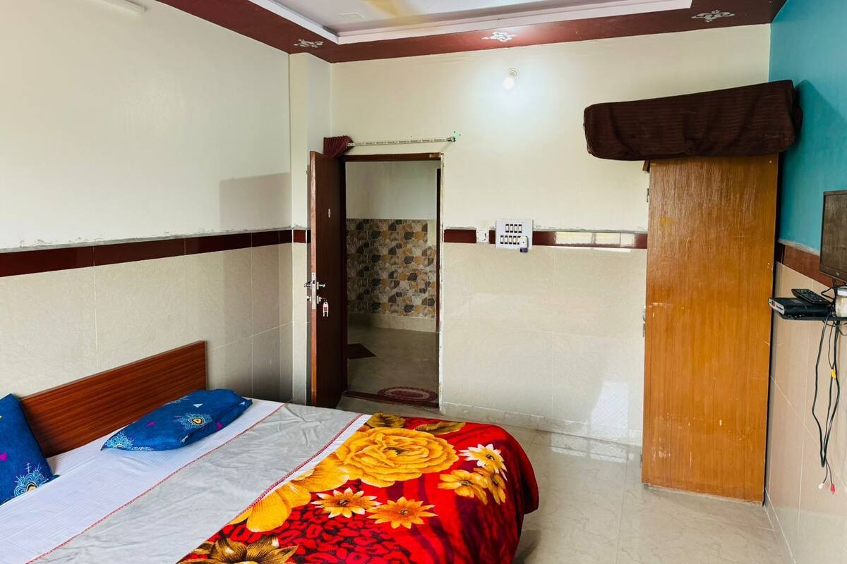 Une chambre à coucher avec un lit, une porte en bois, un ventilateur de plafond et un mur recouvert de carreaux.