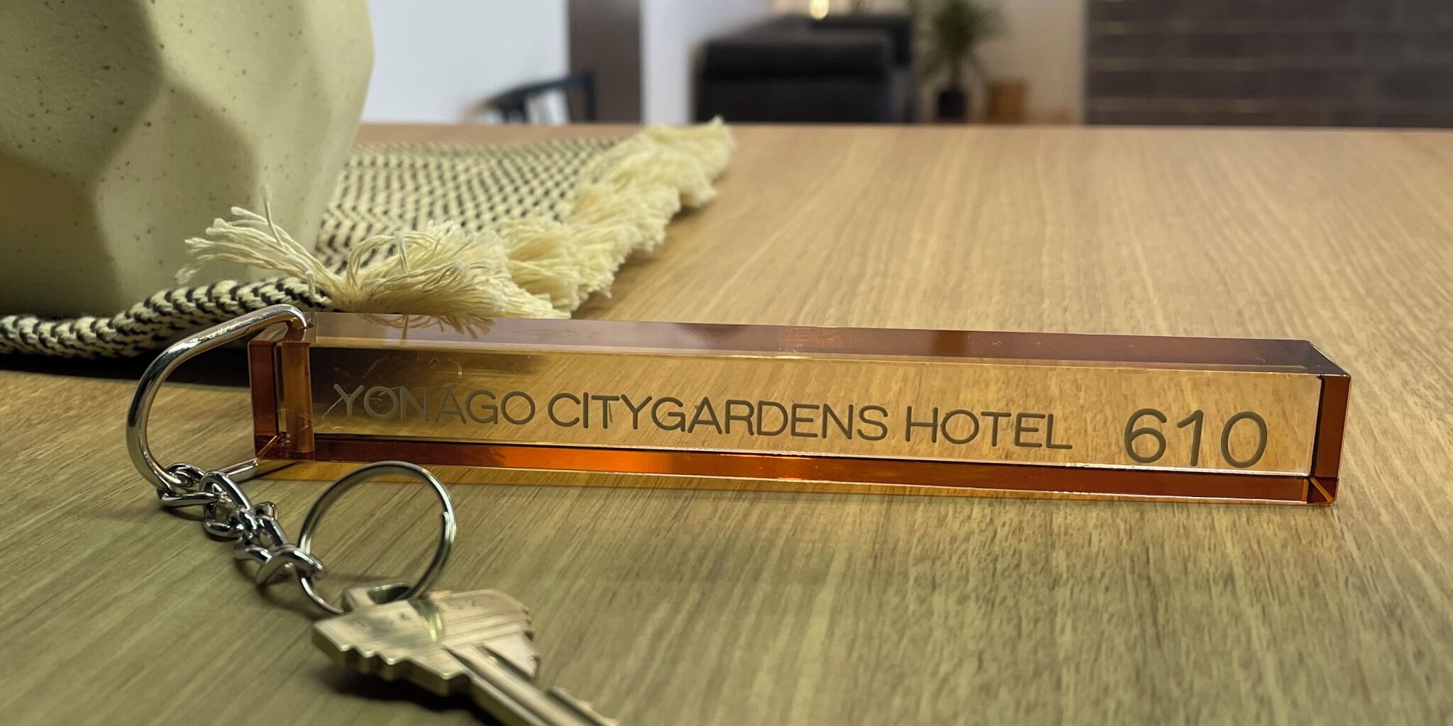 Una placa de hotel con la inscripción 'YONAGO CITYGARDENS HOTEL 610' sobre una mesa de madera.