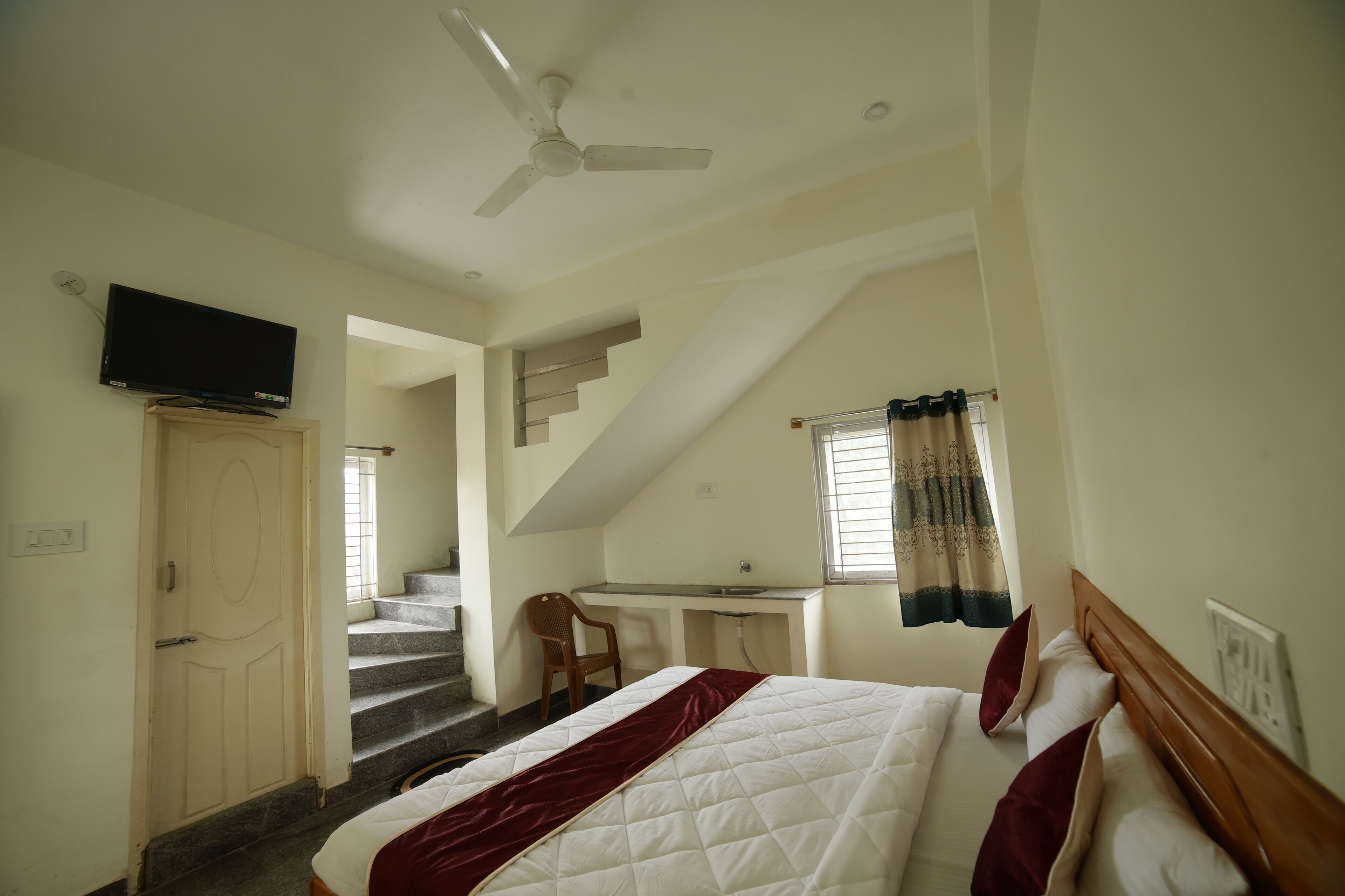 Un dormitorio con cama, escritorio, silla, televisor y escalera.