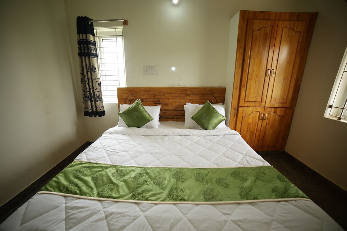 Ein Bett mit einer gesteppten Bettdecke in Weiß und Grün, zwei grüne Kissen und ein Holz-Kopfstück.
