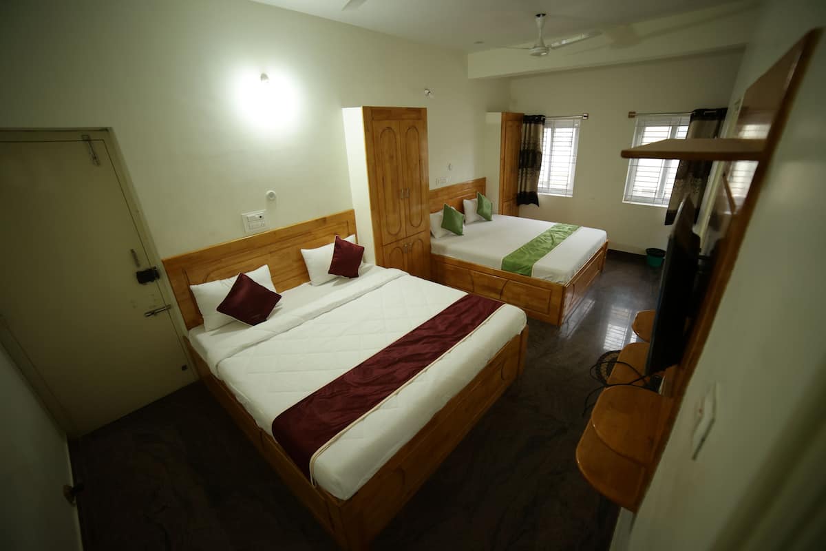 Ein Hotelzimmer mit zwei hölzernen Betten, einem Kleiderschrank, einem Fernseher und einem Deckenventilator.