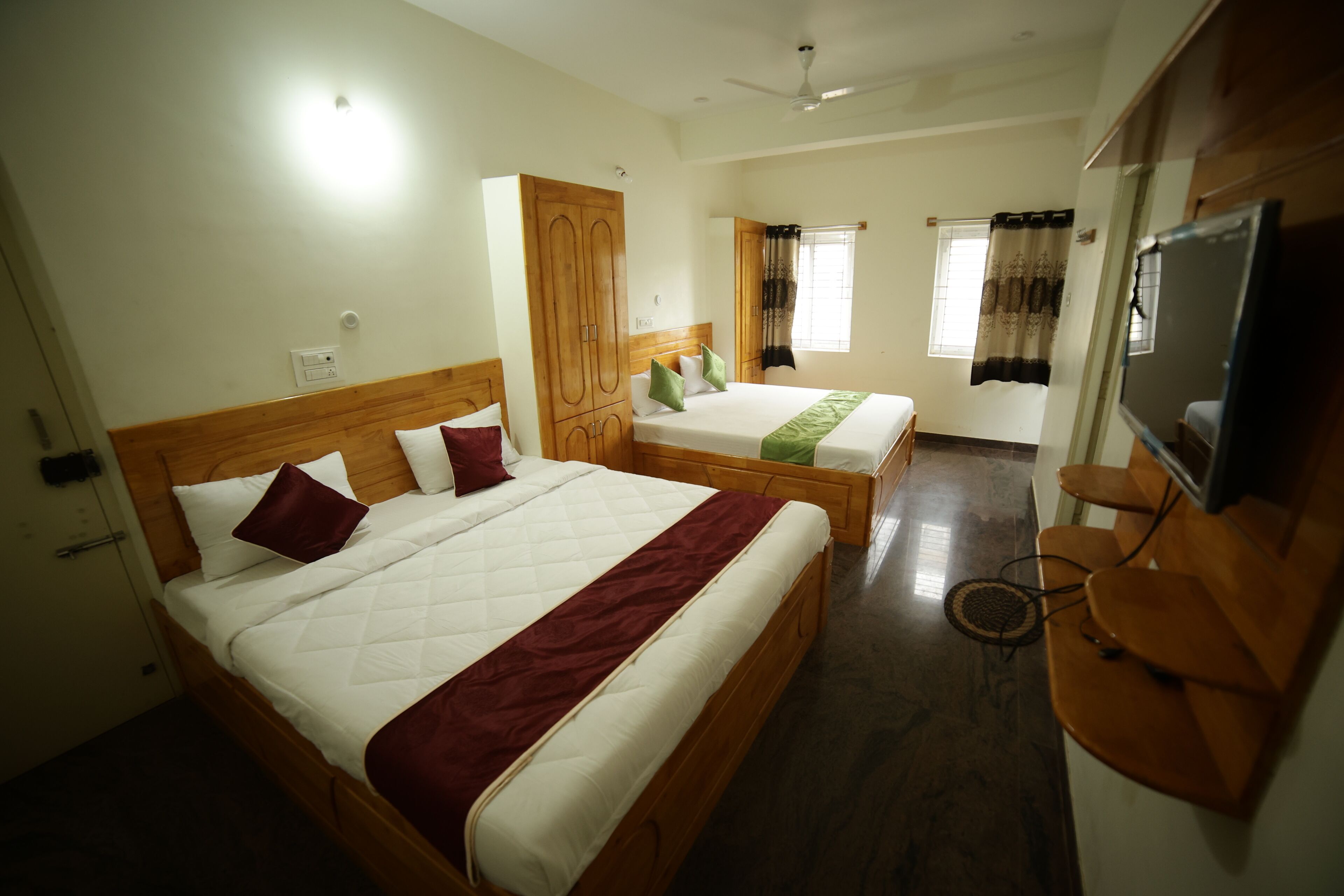 Een hotelkamer met twee bedden, een kledingkast, een televisie en een zithoekje.