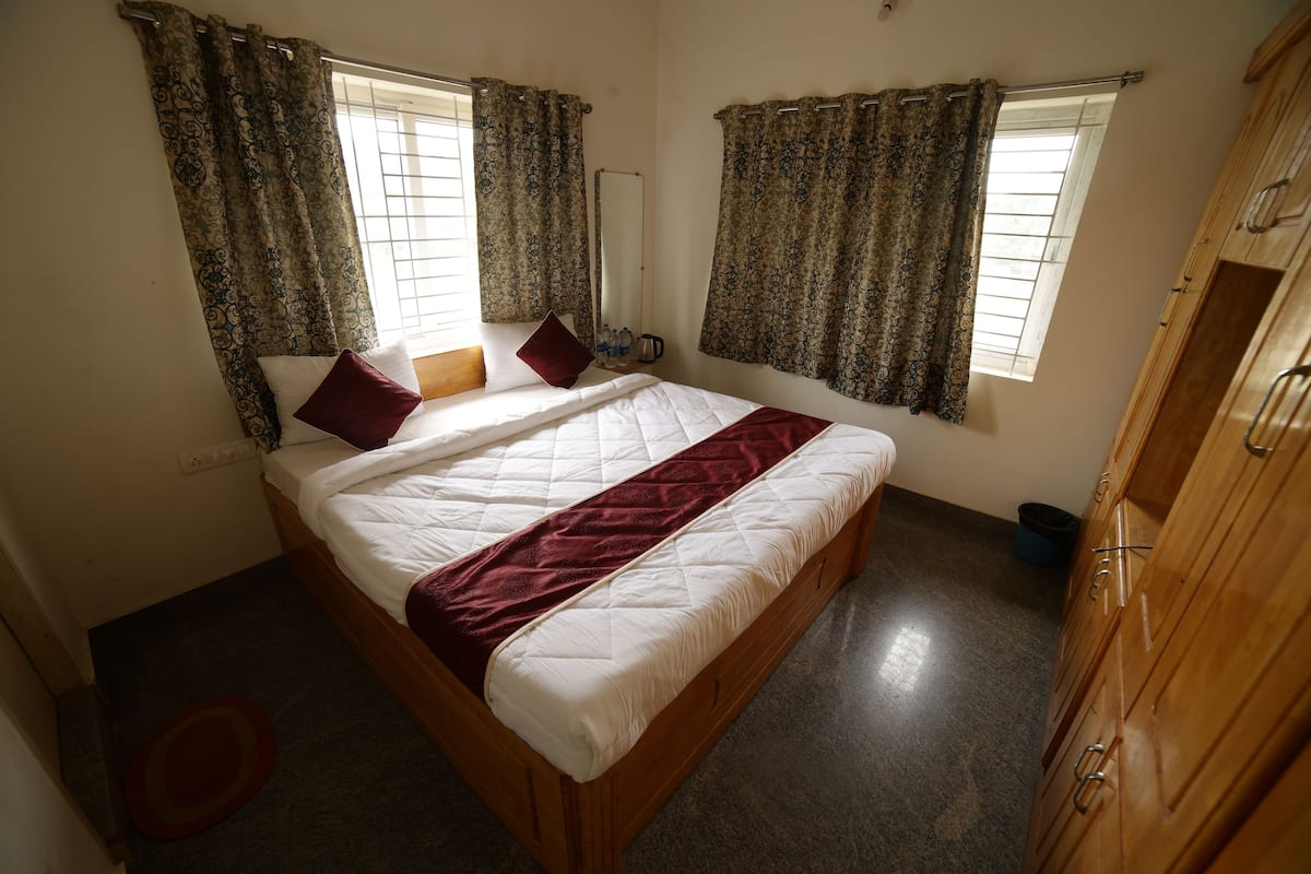 Ein Schlafzimmer mit einem Bett, Vorhängen, einem Kleiderschrank und einem Fenster.