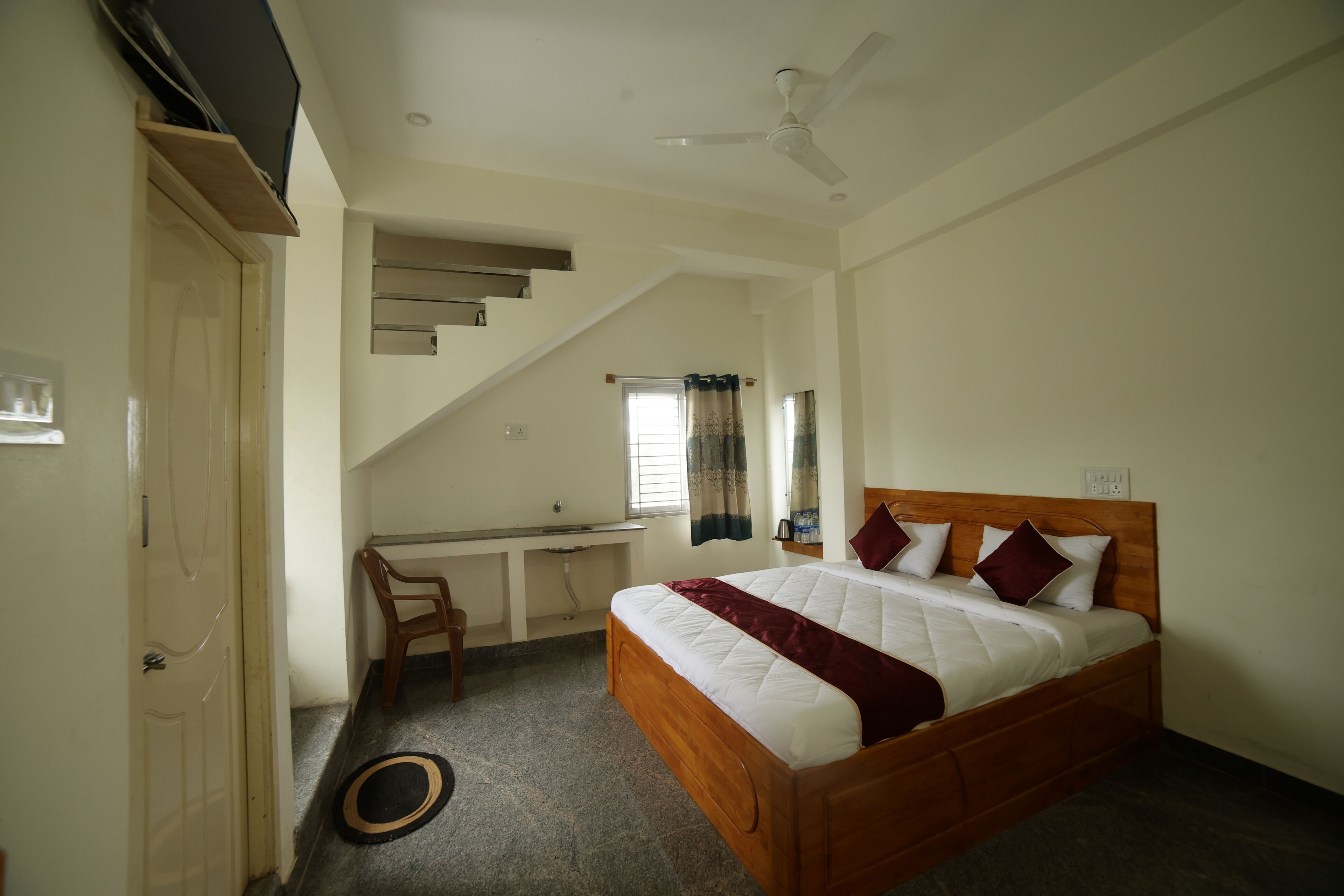Ein Schlafzimmer mit Bett, Schreibtisch, Stuhl und Deckenventilator.